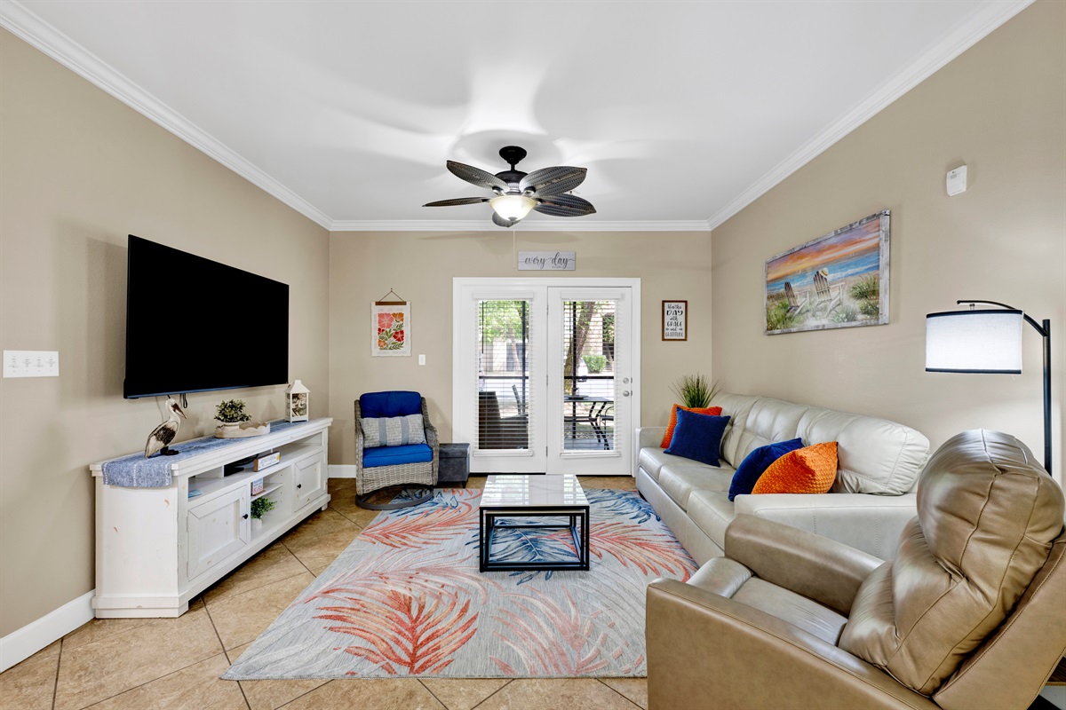 Living room with leather sleeper sofa, recliner, arm chair, ceiling fan and wall mounted smart TV 