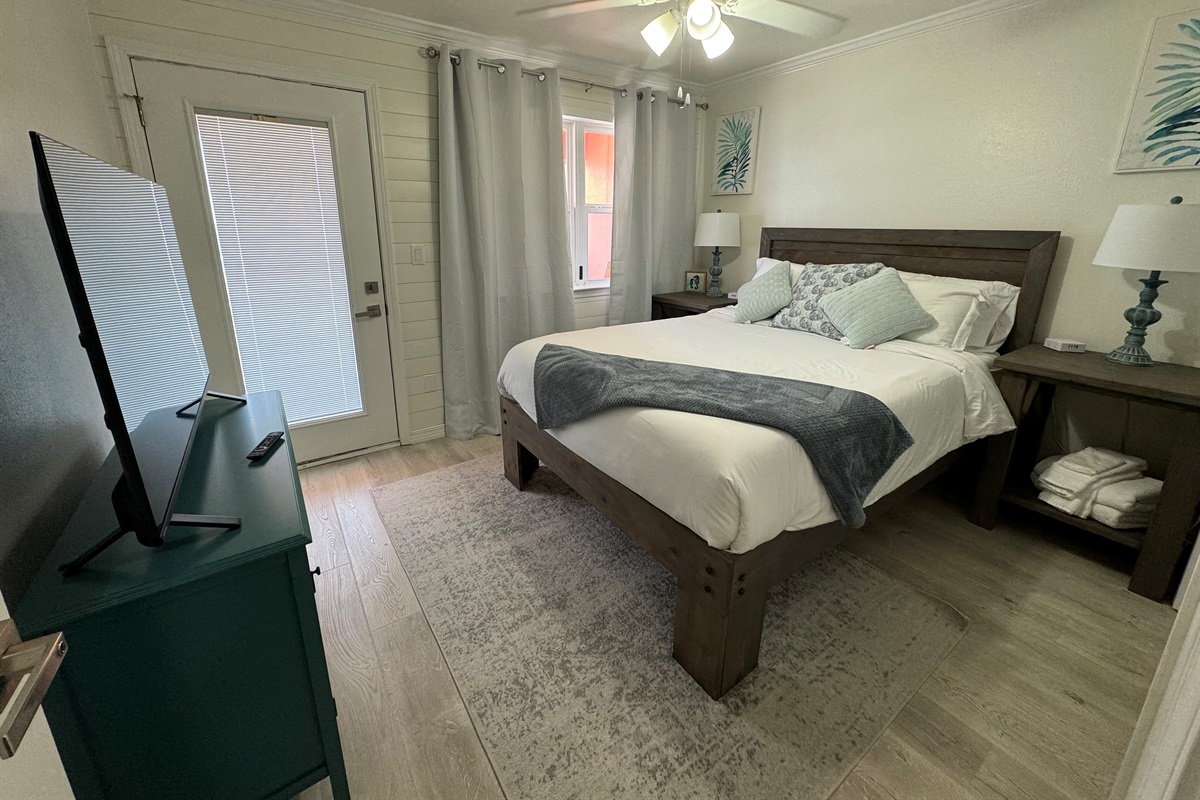 Second bedroom with queen bed and smart tv, balcony access