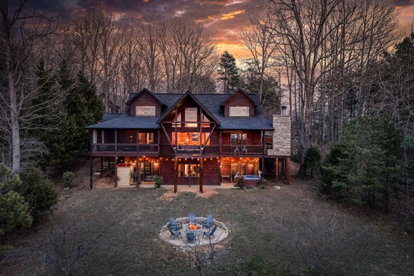 Fire pit and the back yard of the beautiful "Blessed Sunset" mountain retreat home overlooking the back yard! Stunning A-frame, wrap-around porch, screened-in patio, outdoor fireplace, outdoor dining table, sauna, hot tub, outdoor couch, and more!