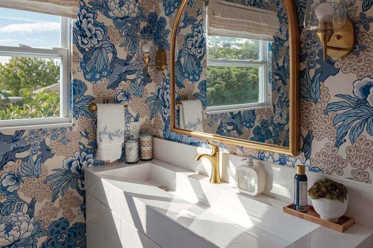 The shared full bathroom delights with colorful wallpaper and impeccable finishes.
