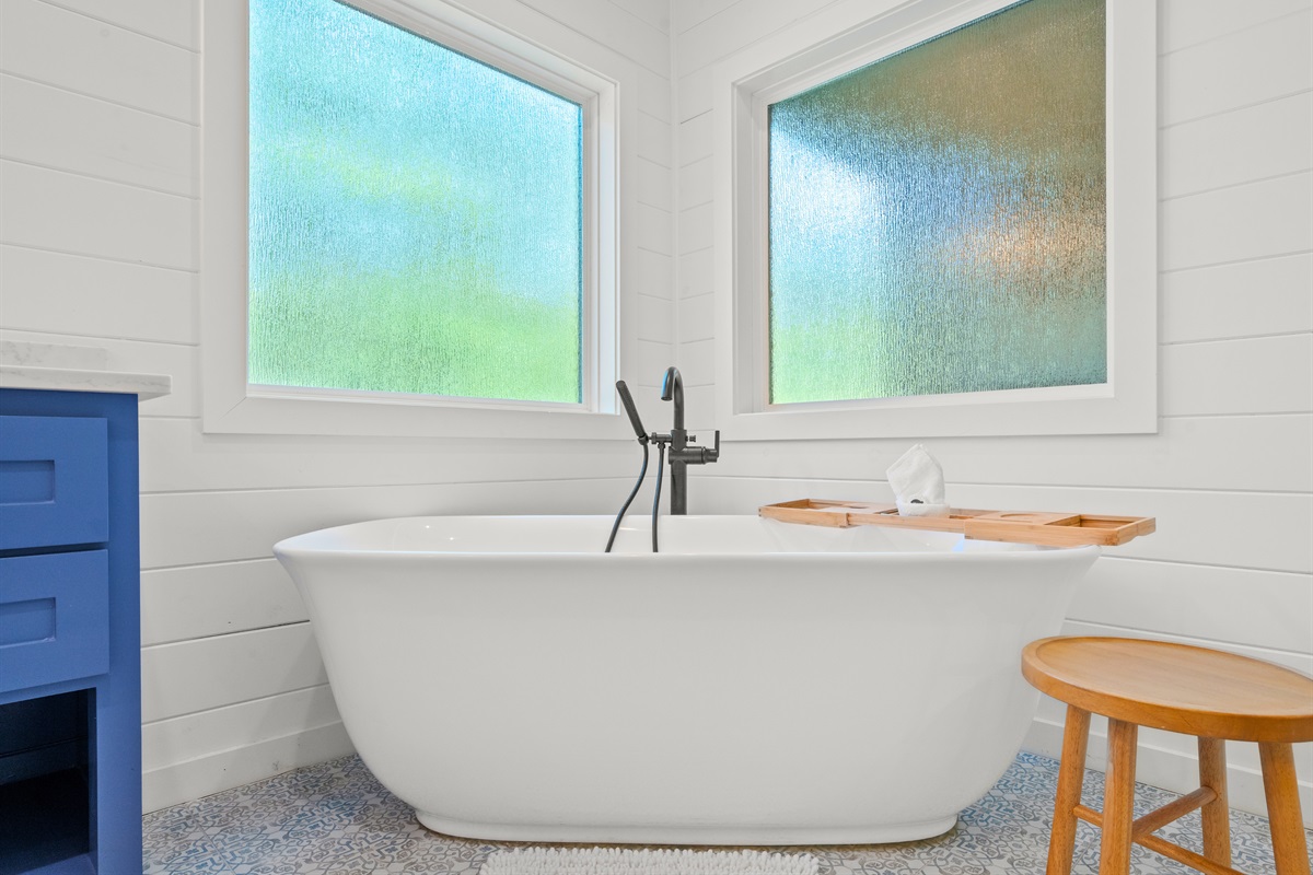 Freestanding soaking tub with wooded views.