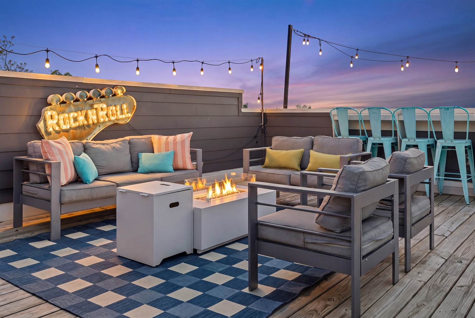 Rooftop Oasis: Enjoy dazzling sunsets by the fire with chic seating and lit by string lights and vibrant Rock & Roll sign!