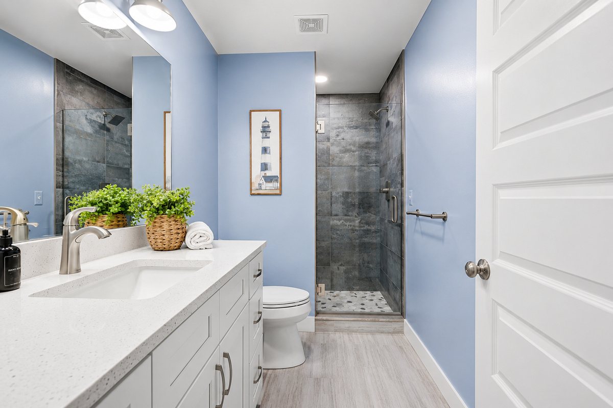 The third-floor full bathroom features a spacious walk-in shower, modern coastal finishes, and a bright, inviting design—perfect for refreshing after a day on the water.