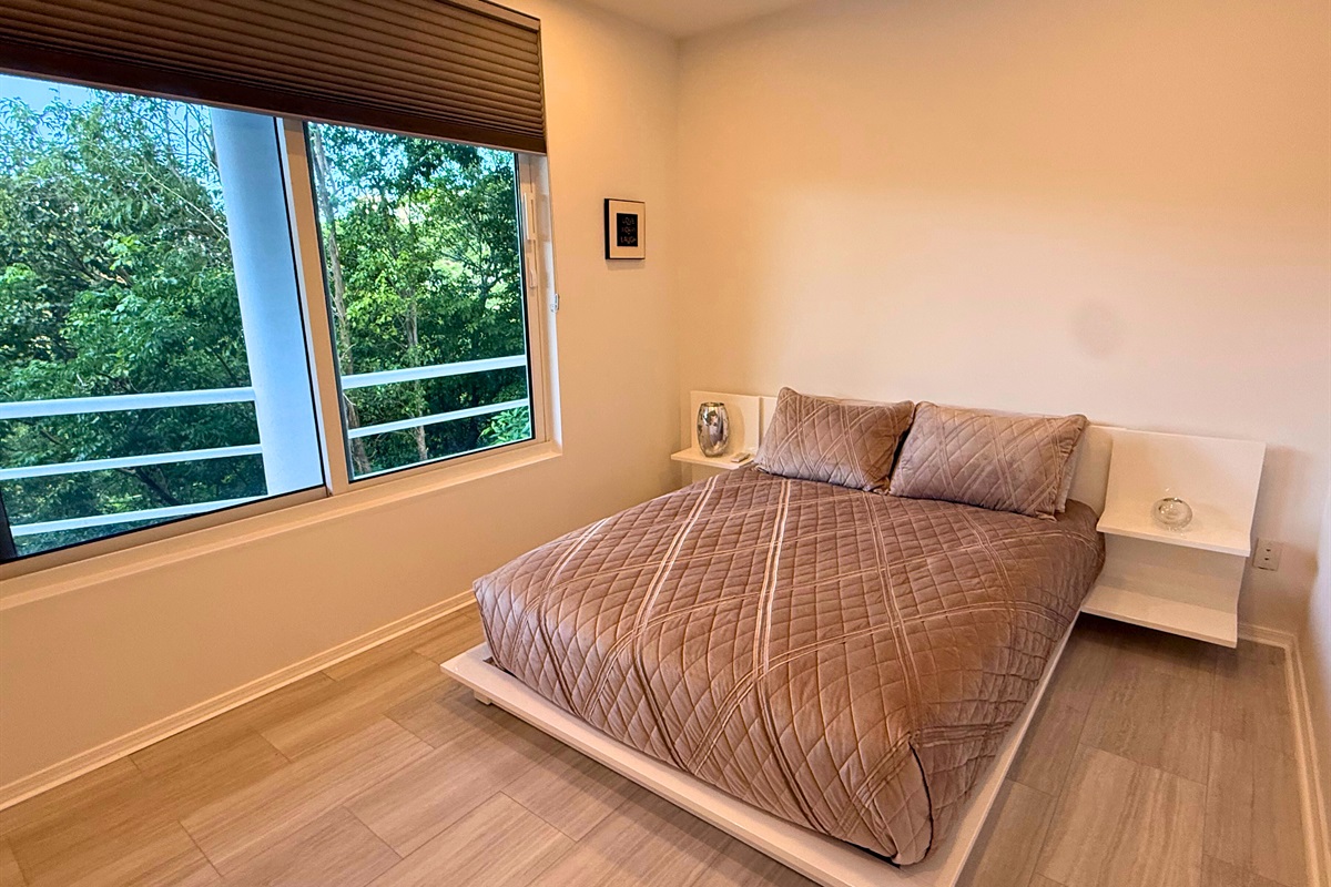 A queen sized bed and large windows in the guest room
