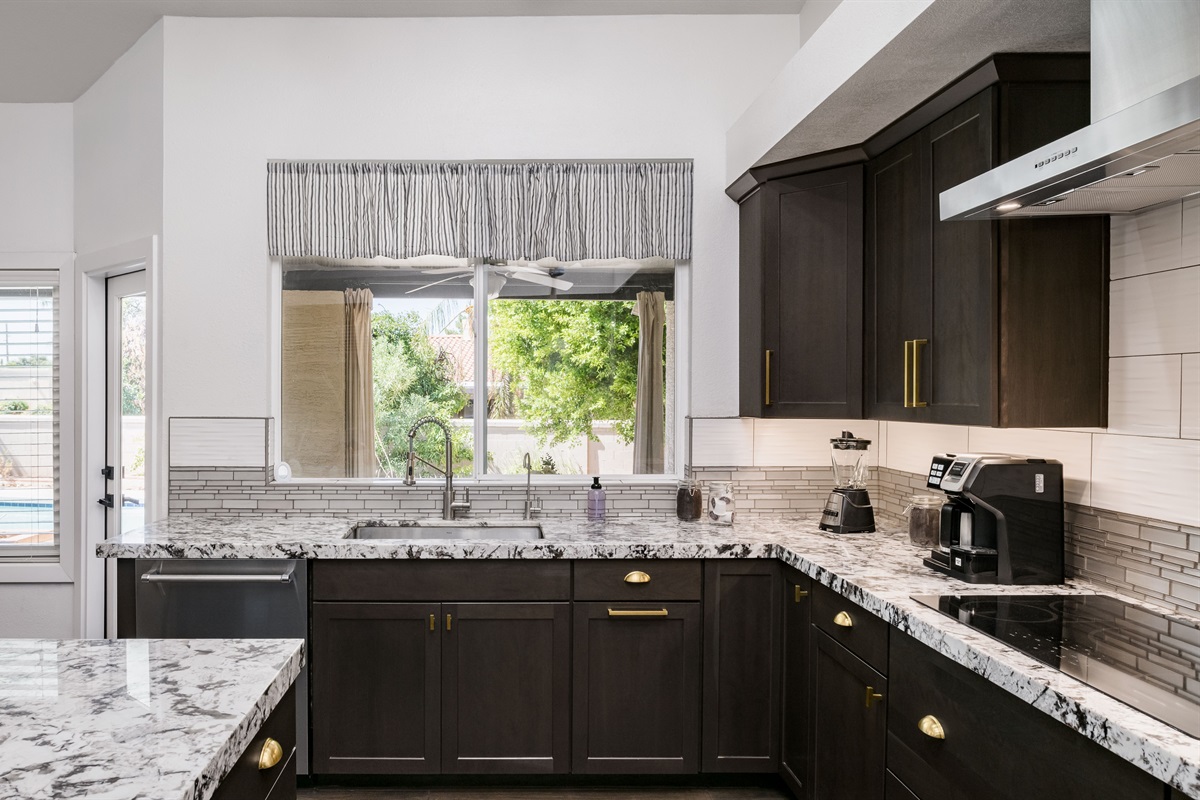 Cook with ease in this gourmet kitchen featuring premium appliances, a commercial fridge, and beautiful backyard views.