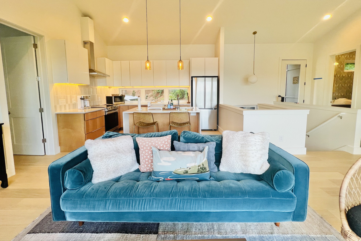 Relax and unwind. The main-level living room offers comfortable seating, a Smart TV, a wood-burning stove, and direct access to the covered deck. Large windows and glass doors keep the lake and mountain views front and center.
