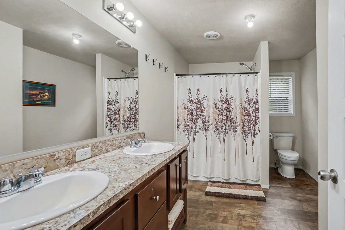 Main bathroom with double sinks, bathtub and shower combination and toilet.