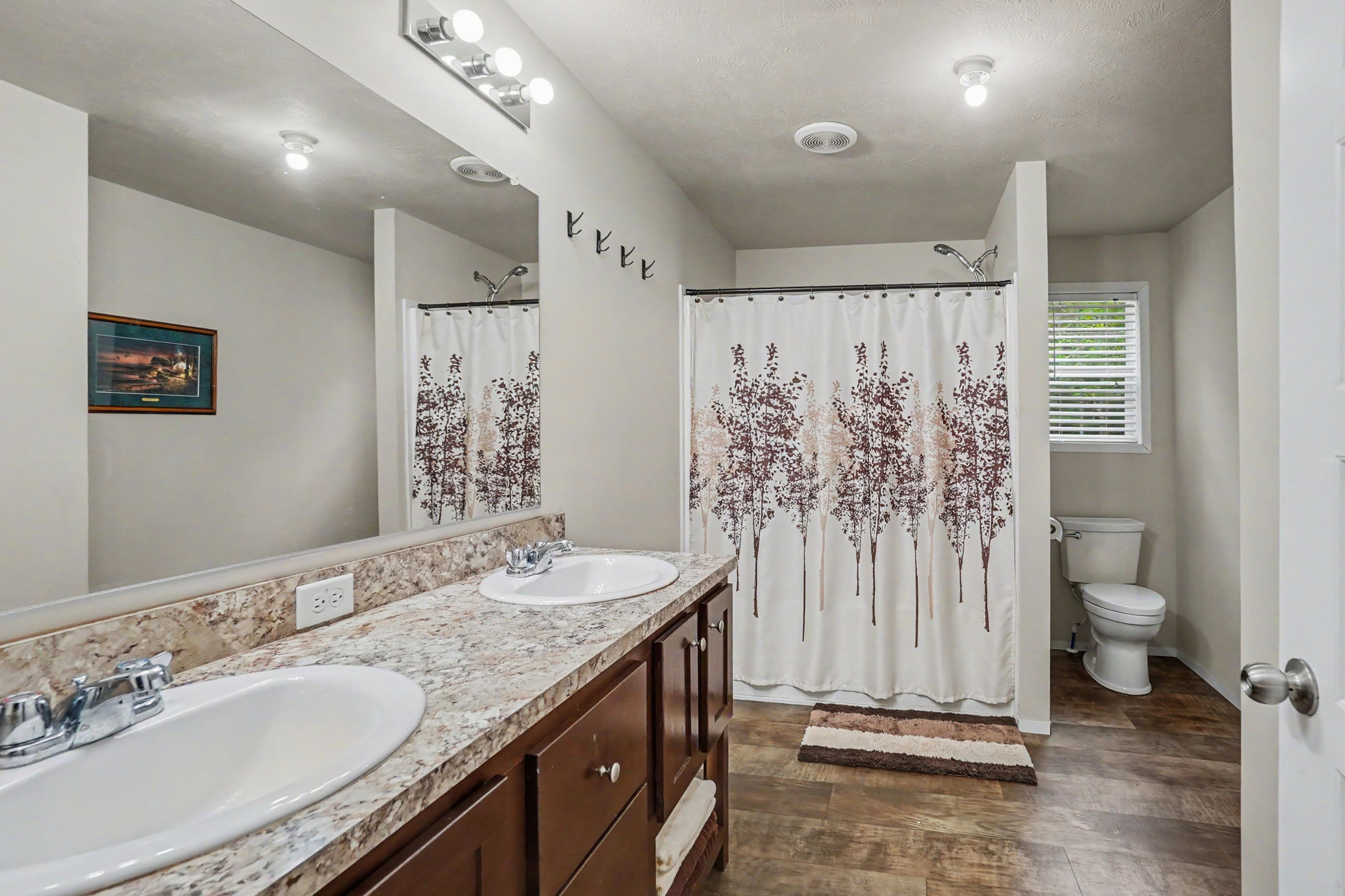 Main bathroom with double sinks, bathtub and shower combination and toilet.
