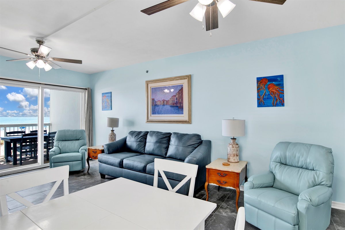 Living room with wall mounted smart TV, 2 ceiling fans, leather sleeper sofa, 2 leather rocker recliners and balcony access with breathtaking view