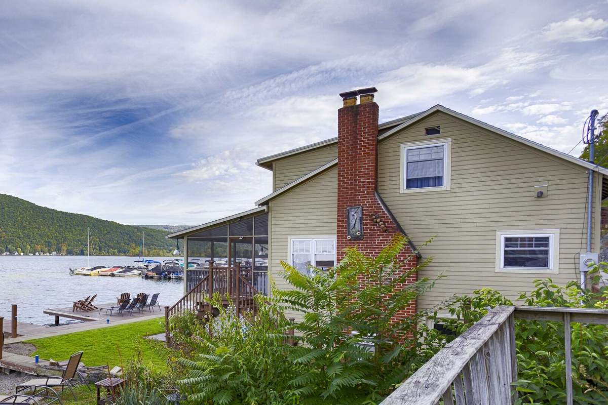 Discover the charm of this remarkable home with a captivating side view that reveals a private dock extending gracefully into the water. From this perspective, the house beautifully blends with its serene lakeside surroundings, offering the perfect s