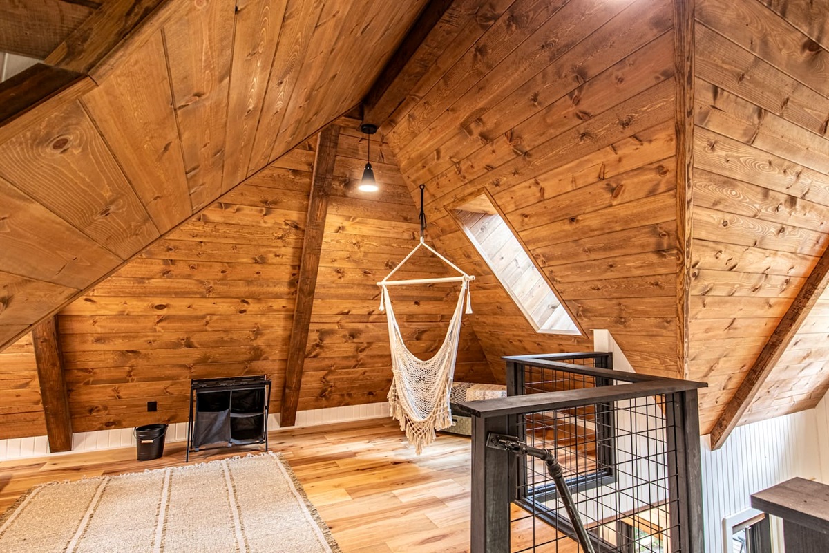 Adding a playful touch, a hammock is ingeniously built into the floor, perfect for lounging and soaking in the serene atmosphere. Nearby, a macrame swing hangs, providing a cozy nook to relax and sway gently while enjoying the tranquil forest view.