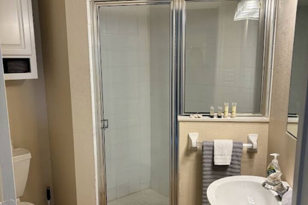 Bathroom with a shower enclosure, pedestal sink, and clean neutral finishes.