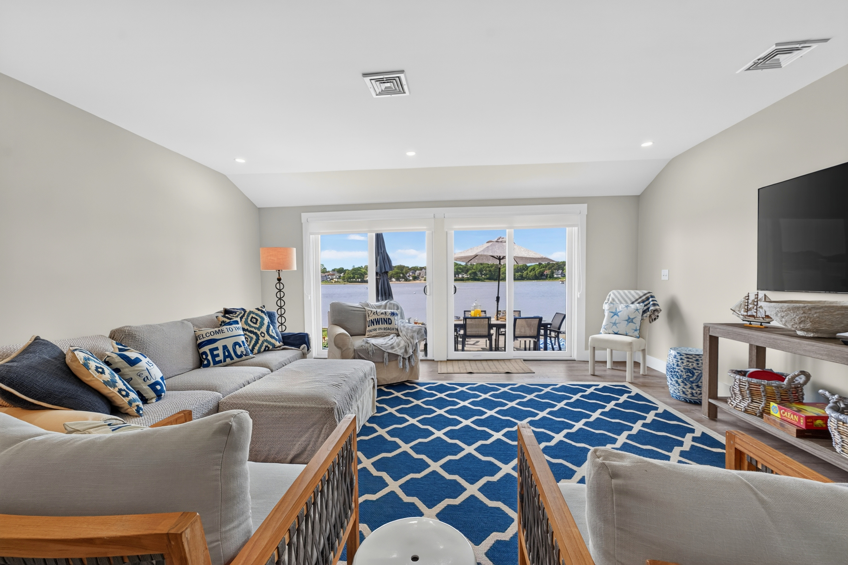 Spacious family room featuring comfortable sofas, large windows, and breathtaking waterfront views.