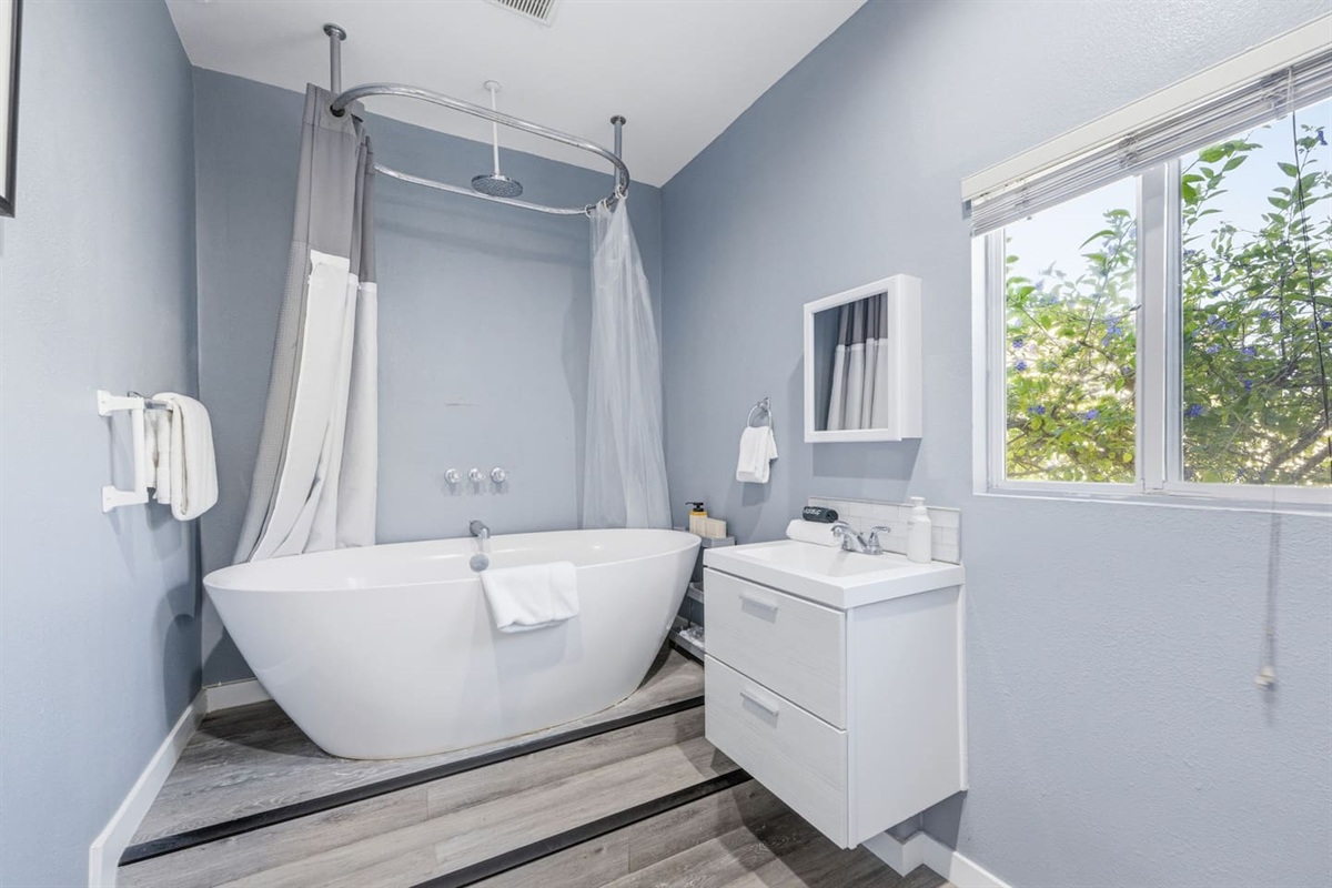 Full bathroom with soaking tub, shower combo, and vanity. Complimentary shampoo, conditioner, and shower gel provided.