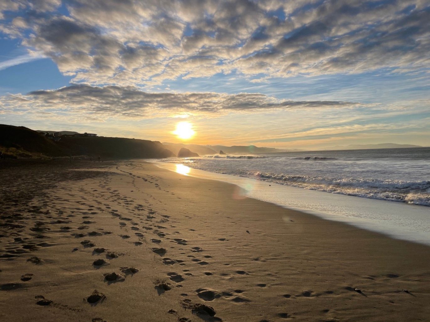Footprints in the sand beneath a glowing sunrise
