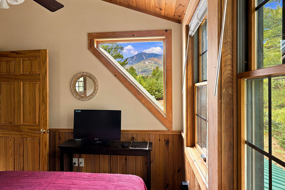 This bedroom includes a television, work desk, and a picture window framing Whiteface Mountain.