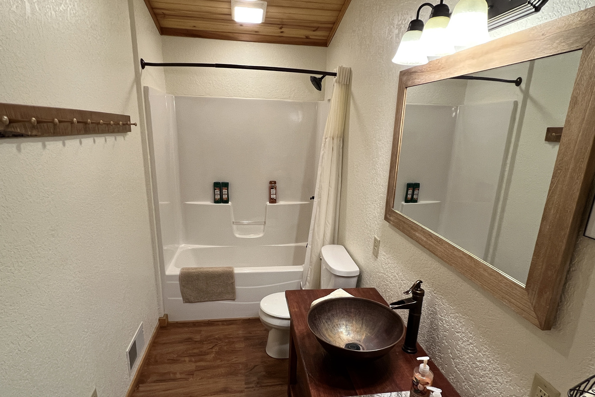 Entry level bath has large custom vanity with copper vessel sink and soft towels