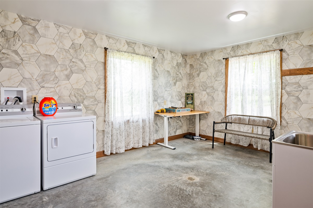 Large laundry and utility room with washer/dryer, folding space, and creative wall textures.