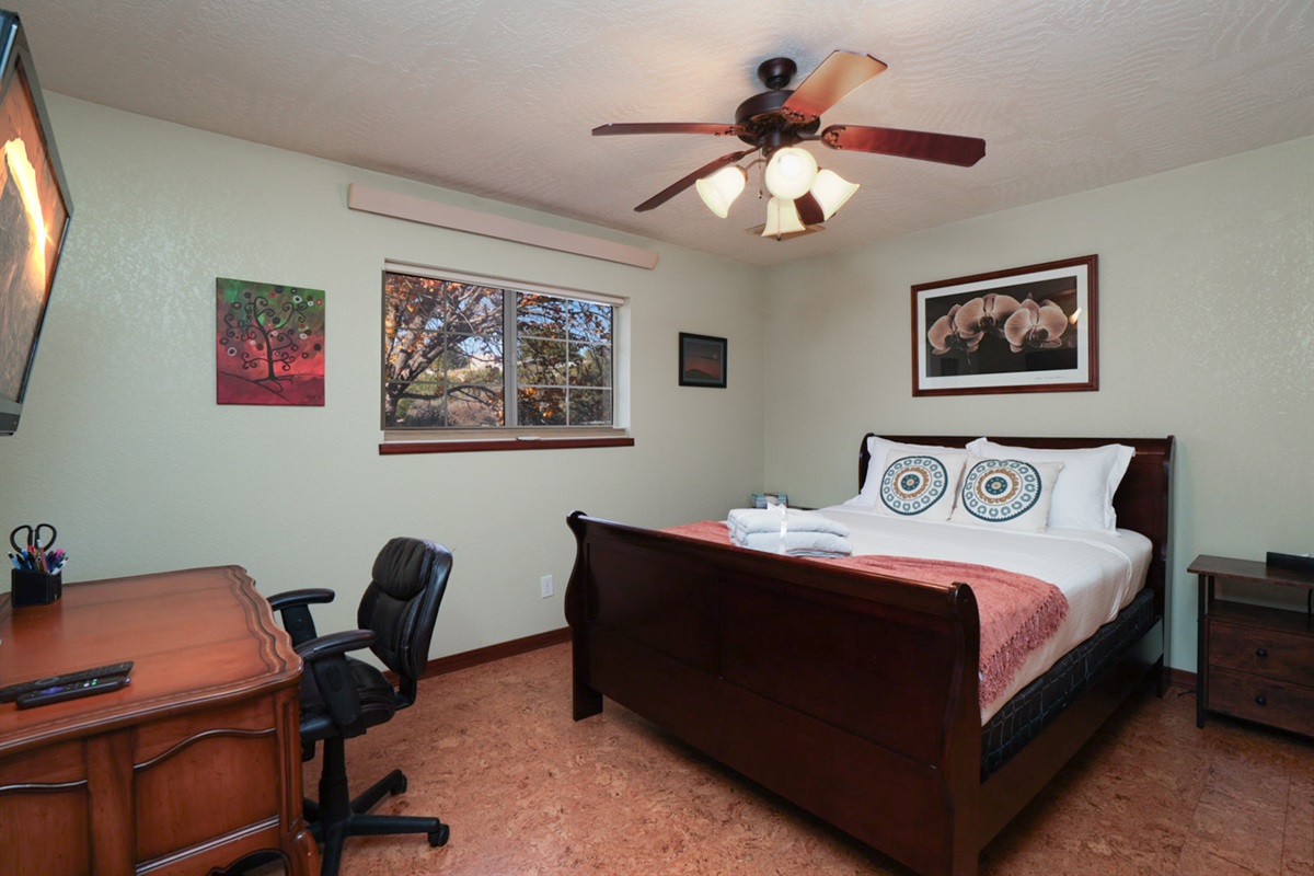 Cozy queen bedroom with smart TV, workspace, and closet—perfect for remote work or a peaceful night’s sleep.
