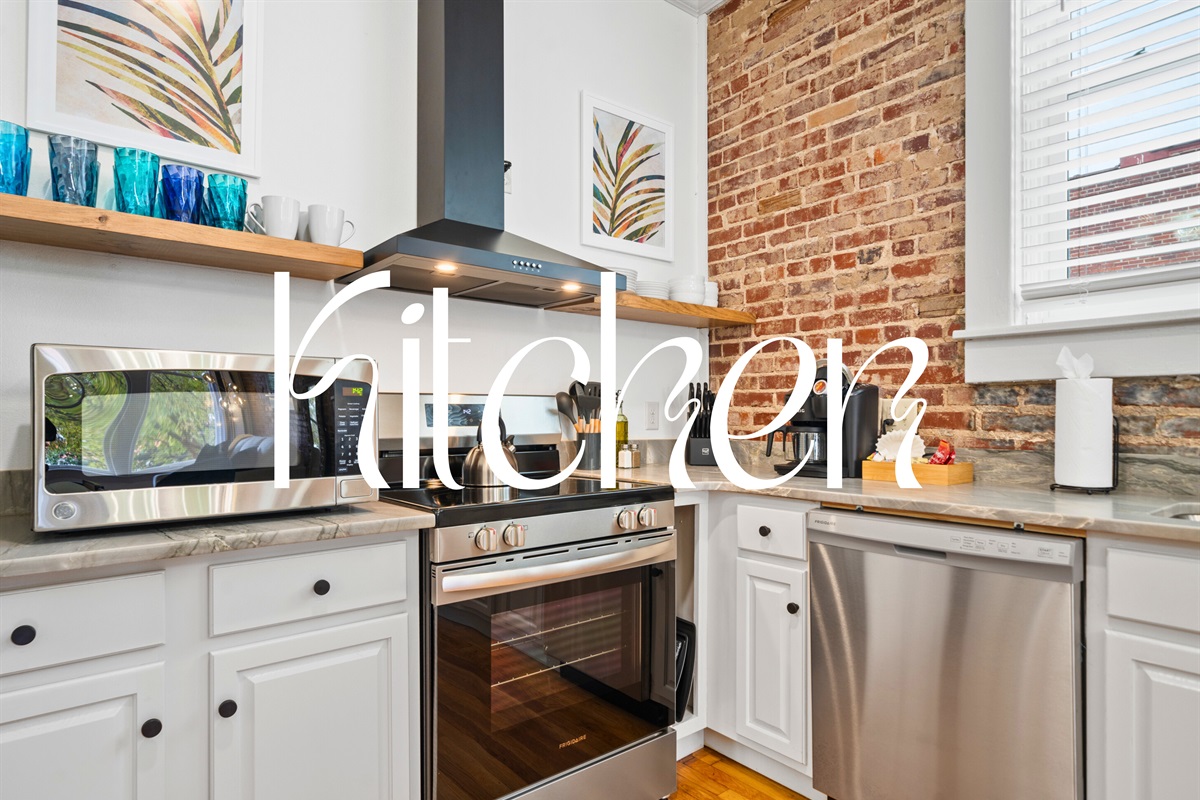 The kitchen features sleek appliances, counter space, and exposed brick that combines modern style with rustic charm.