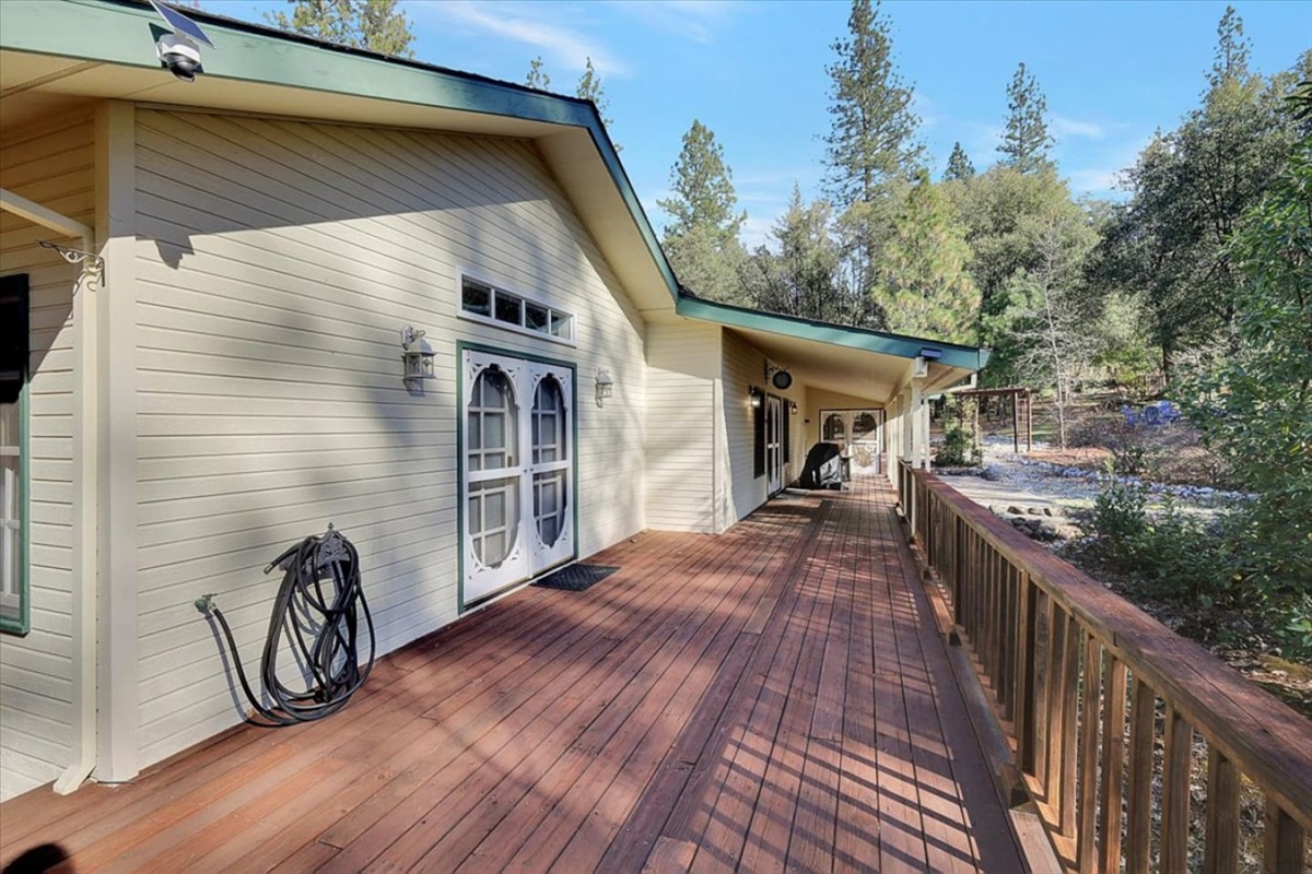 Covered porch with wood decking, wooded views, and plenty of space to walk or sit outside.
