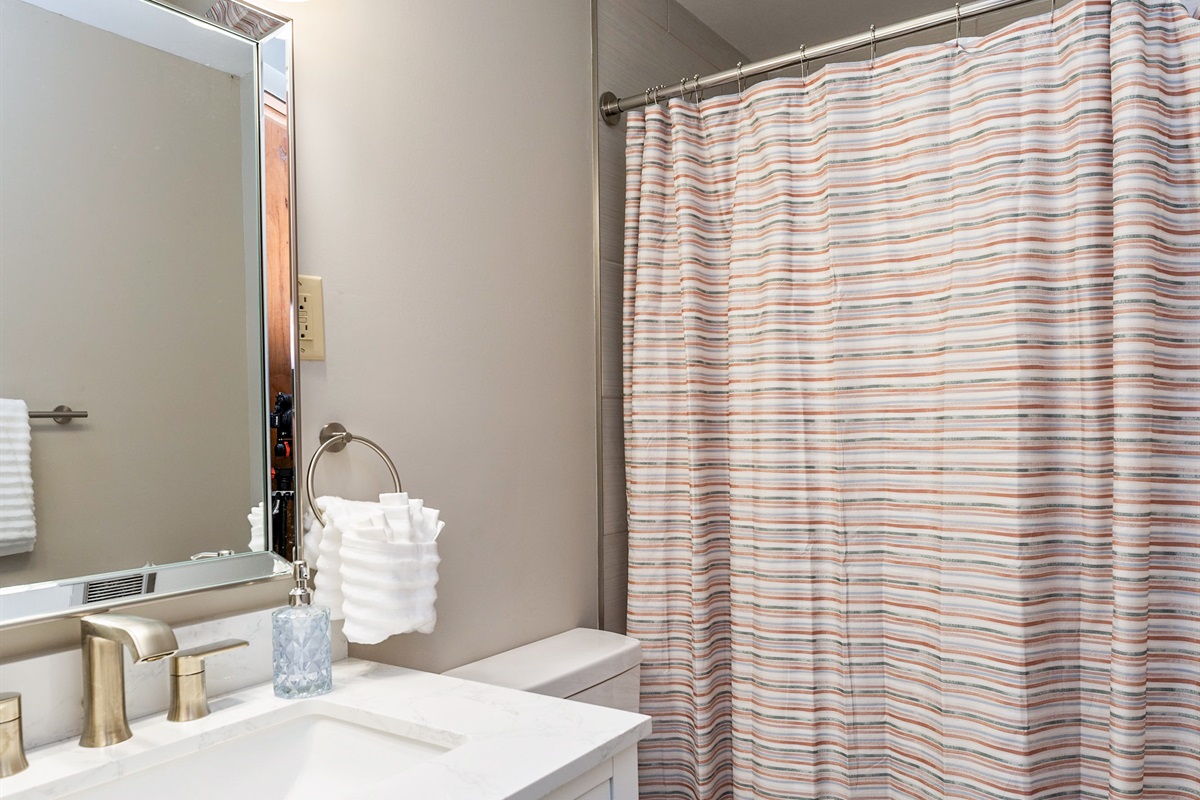 Fresh and modern bathroom with sleek fixtures, a marble vanity, and a cozy shower/tub combo—perfect for unwinding after a day of exploring.