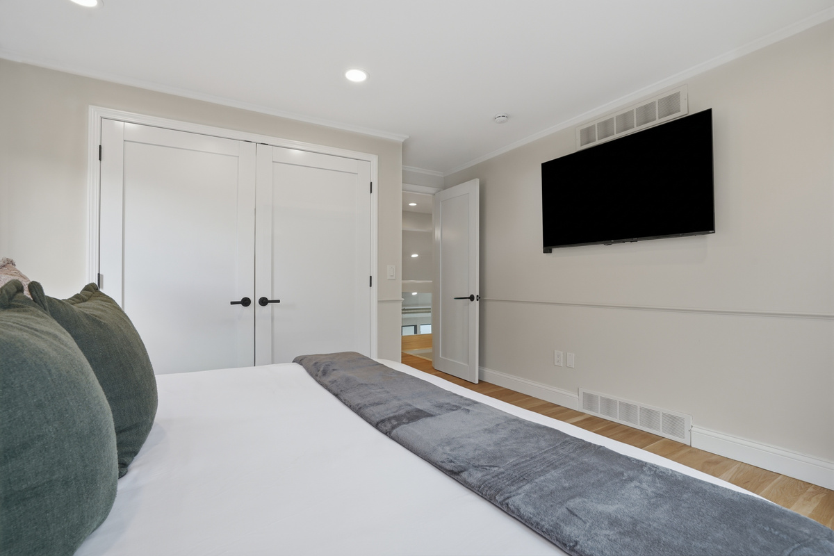 Bright, modern bedroom with a wall-mounted TV, clean neutral finishes, and a comfortable minimalist design. A simple, relaxing space ideal for unwinding and rest during your stay.