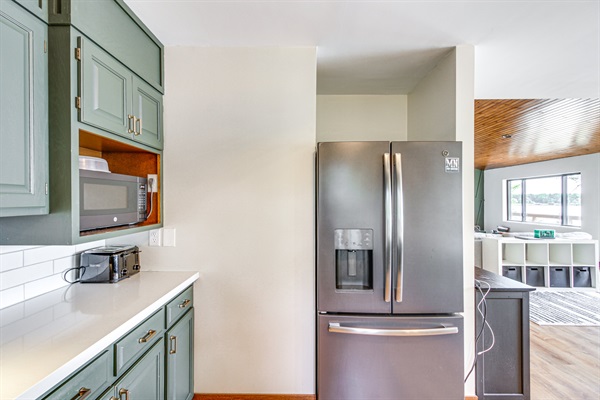 Fully equipped kitchen with stainless steel refrigerator, microwave, and ample counter space