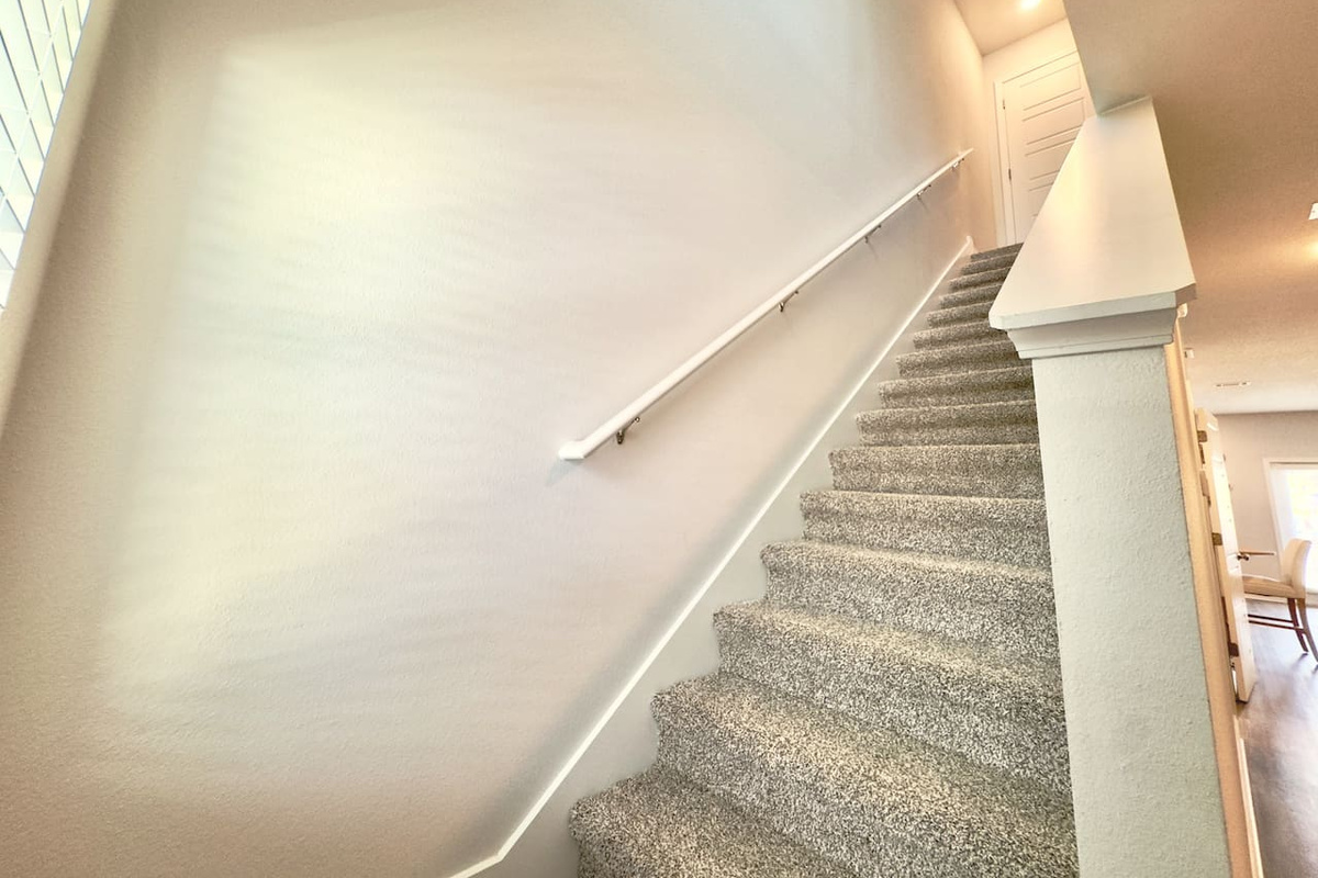 Handrail smooth under your palm, carpeted steps soft and sturdy. Easy climb, quiet, leading you up to the bedrooms.