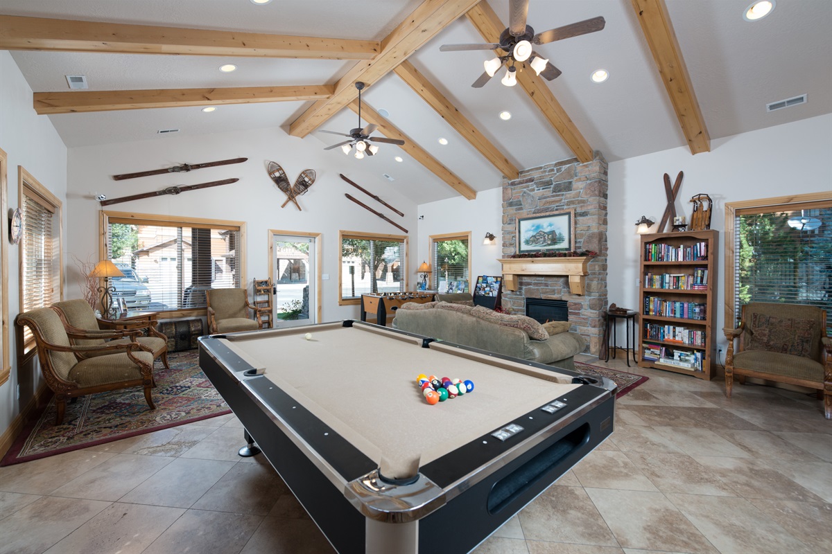 An expansive, lodge-style game room featuring vaulted ceilings, a pool table, and cozy seating—designed for upscale entertainment and relaxation.