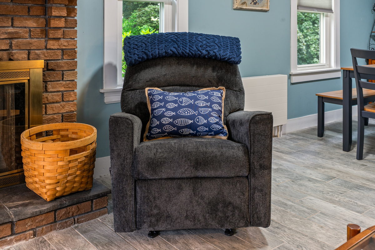 Claim the best seat in the house next to the fireplace. Draped with a warm navy knit blanket and a fun coastal pillow, this comfortable armchair is the perfect spot to unwind, read a favorite book, or relax after your latest Downeast adventure.