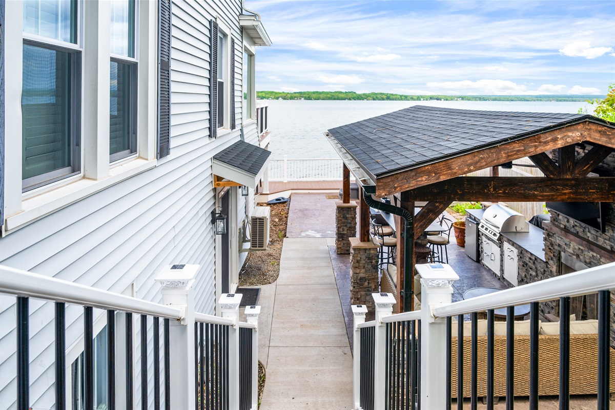 Enjoy lake views as you descend toward a luxury outdoor lounge and kitchen—your path to waterfront bliss 🏞️👣🔥