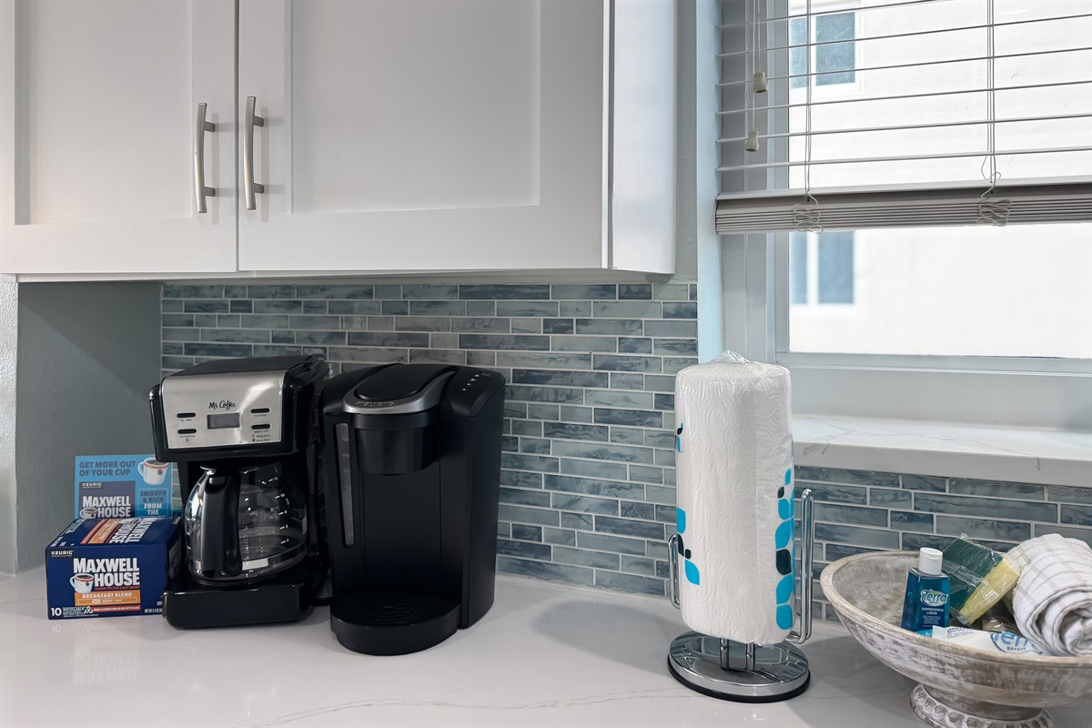 Enjoy your morning brew with both a traditional coffee pot and a single-serve machine, complemented by countertop essentials in this well-equipped kitchen.