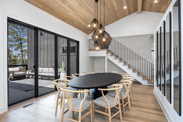 Gather your group around the large dining table with views of the outdoor deck and woods beyond—perfect for shared meals and memories.