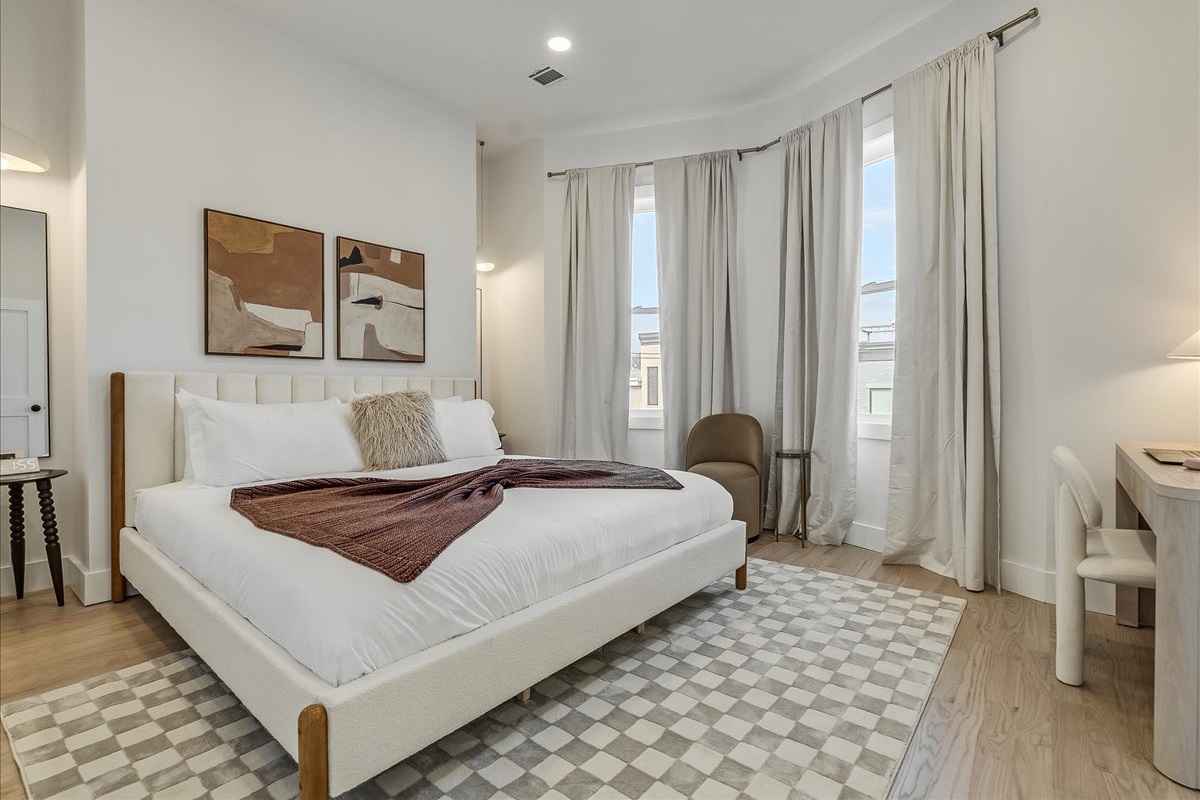Modern bedroom with large bed and flat-screen TVs for guests’ comfort.