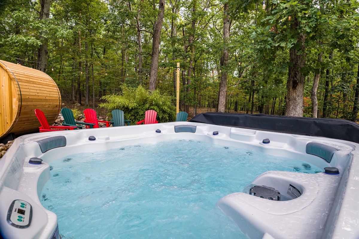 Jets running, water steaming, red Adirondack chair just visible at the edge — the hot tub is always ready and the woods are always quiet.