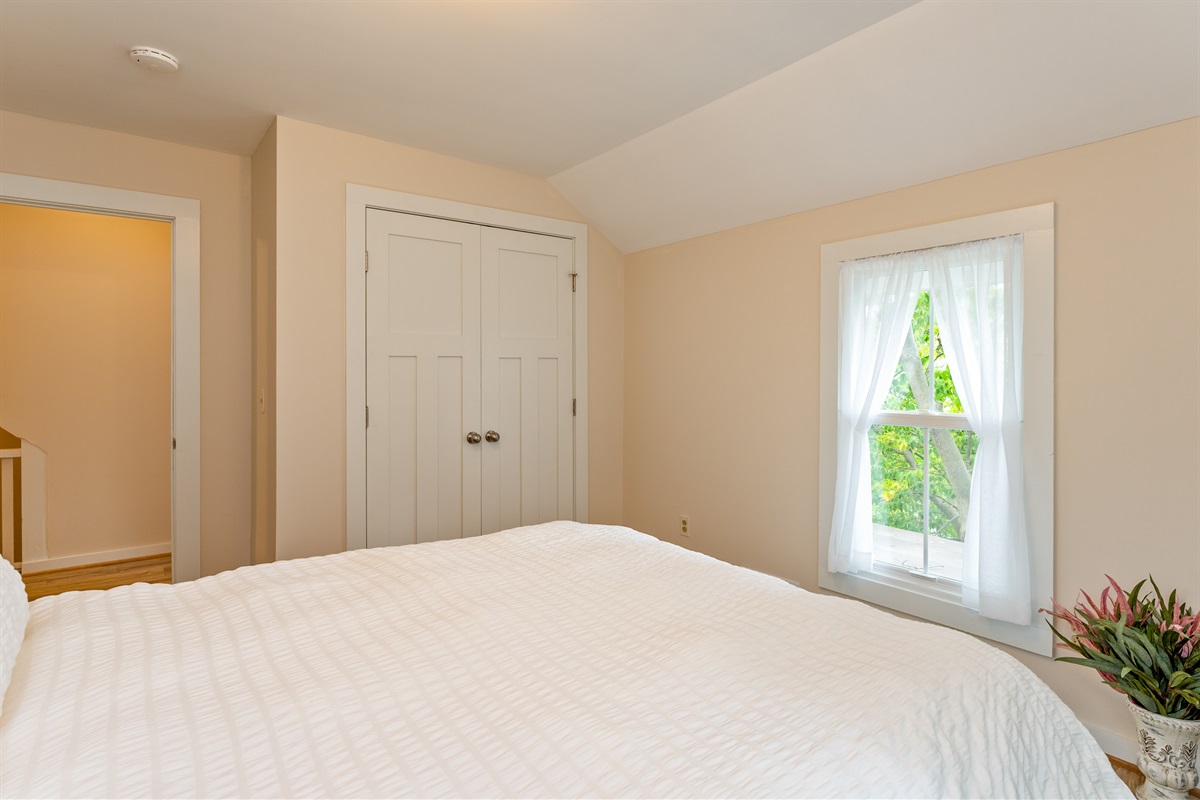 Inviting bedroom with serene views, soft natural light, and a plush white comforter for restful nights. Bedroom #1 queen