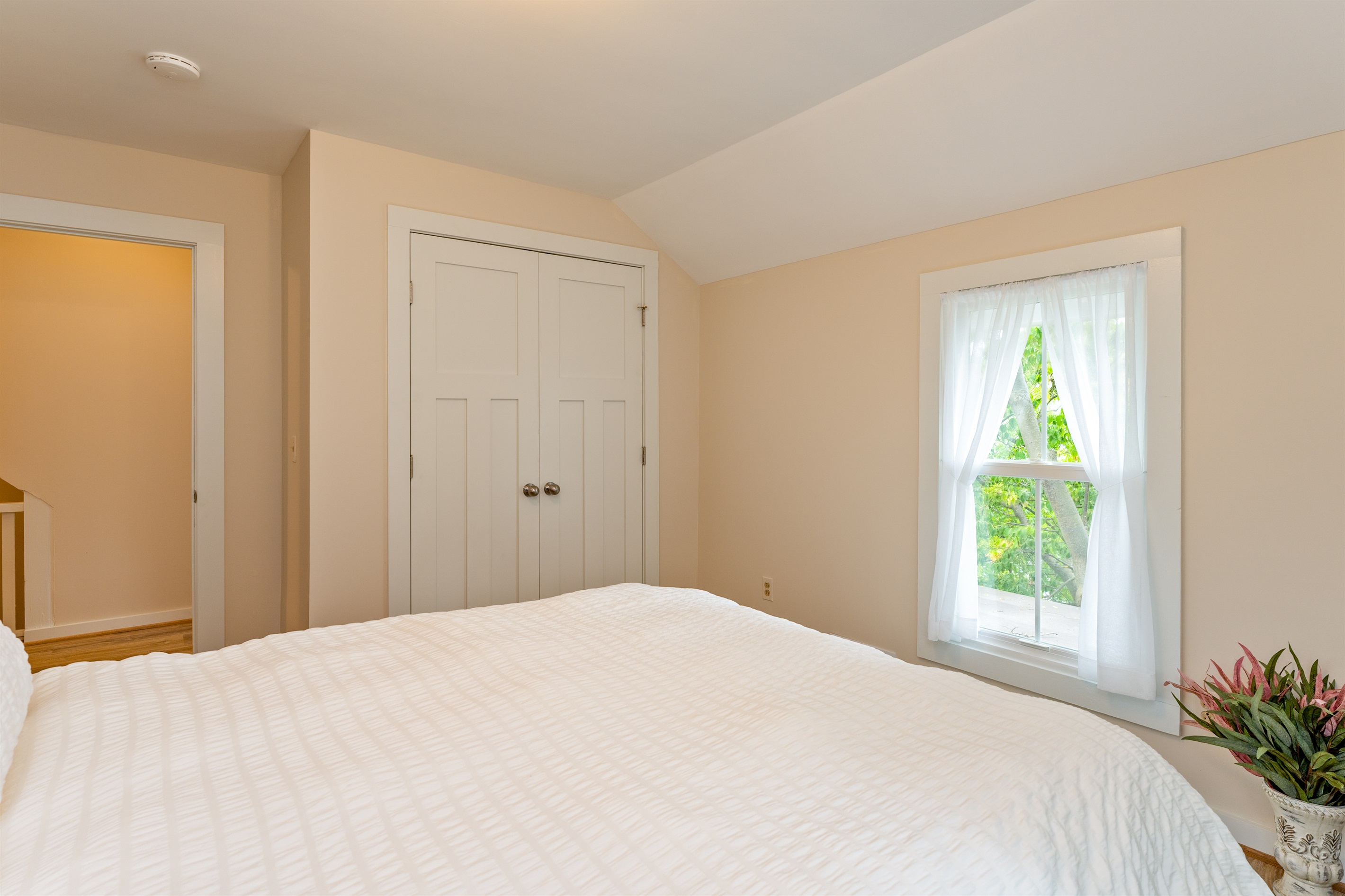 Inviting bedroom with serene views, soft natural light, and a plush white comforter for restful nights. Bedroom #1 queen