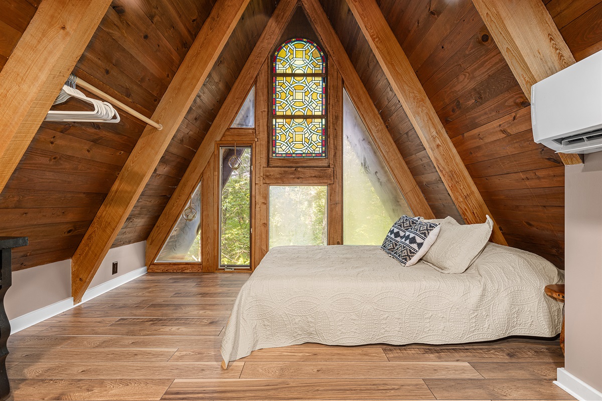 At the back of the loft, find a queen bed with dresser and luggage rack.