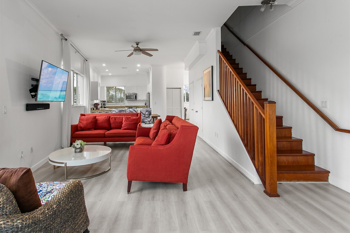 Huge sunny corner living room with two sofas, a daybed, and a swing chair. Private balcony with city and waterway views.