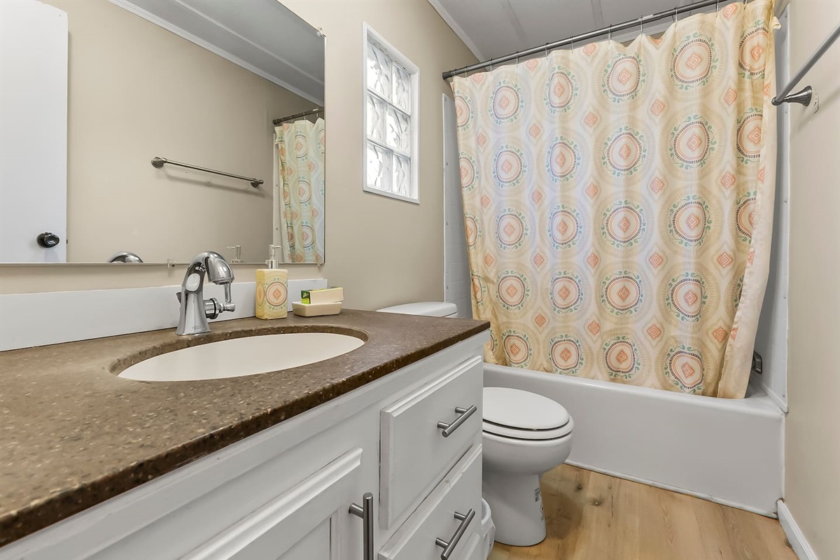 Second bathroom with a full shower-tub combo and patterned curtain for a cheerful touch.