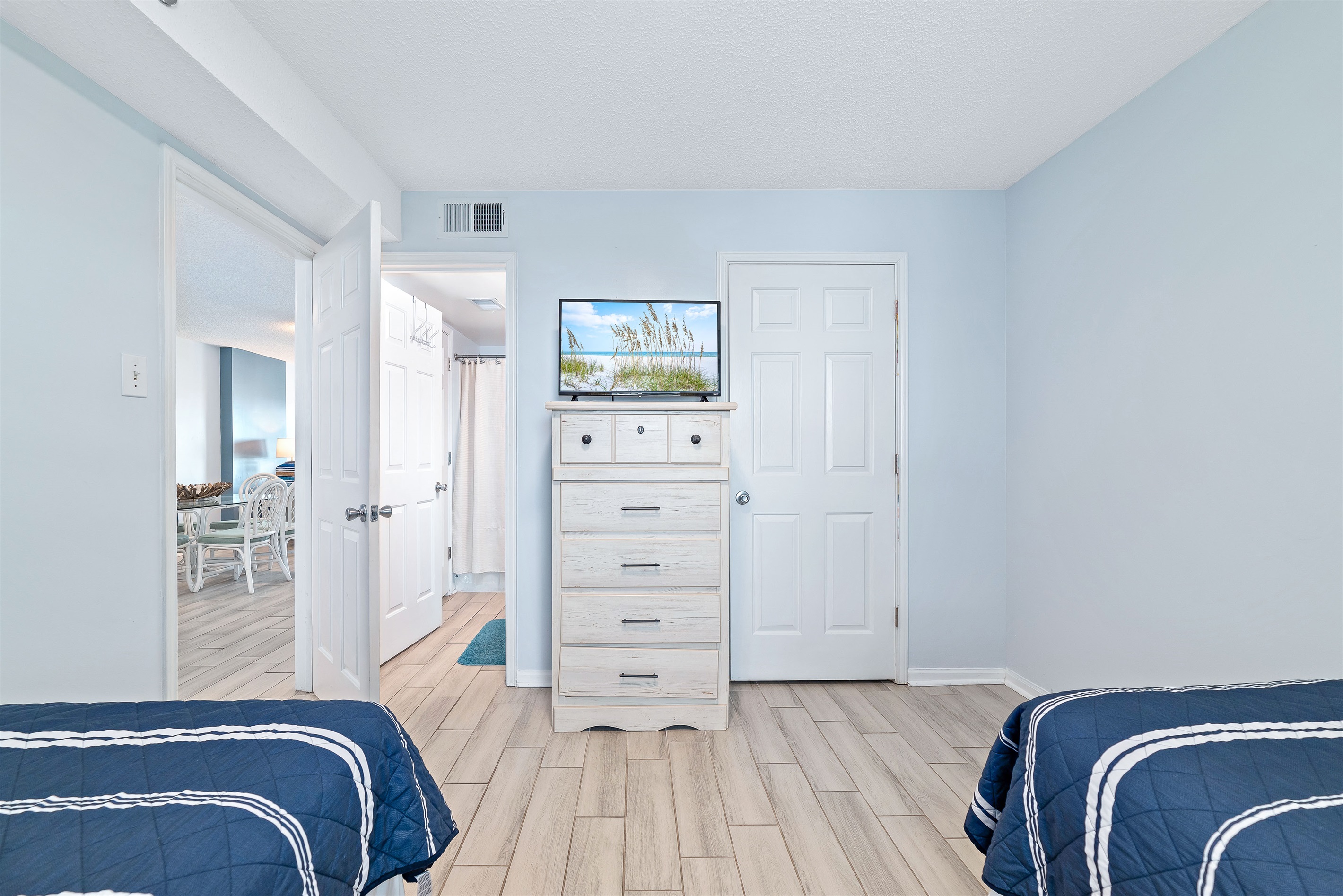 A charming Twin bedroom featuring an ensuite bathroom, flat-screen TV and dresser, perfect for sharing and relaxation after a day of coastal adventures.