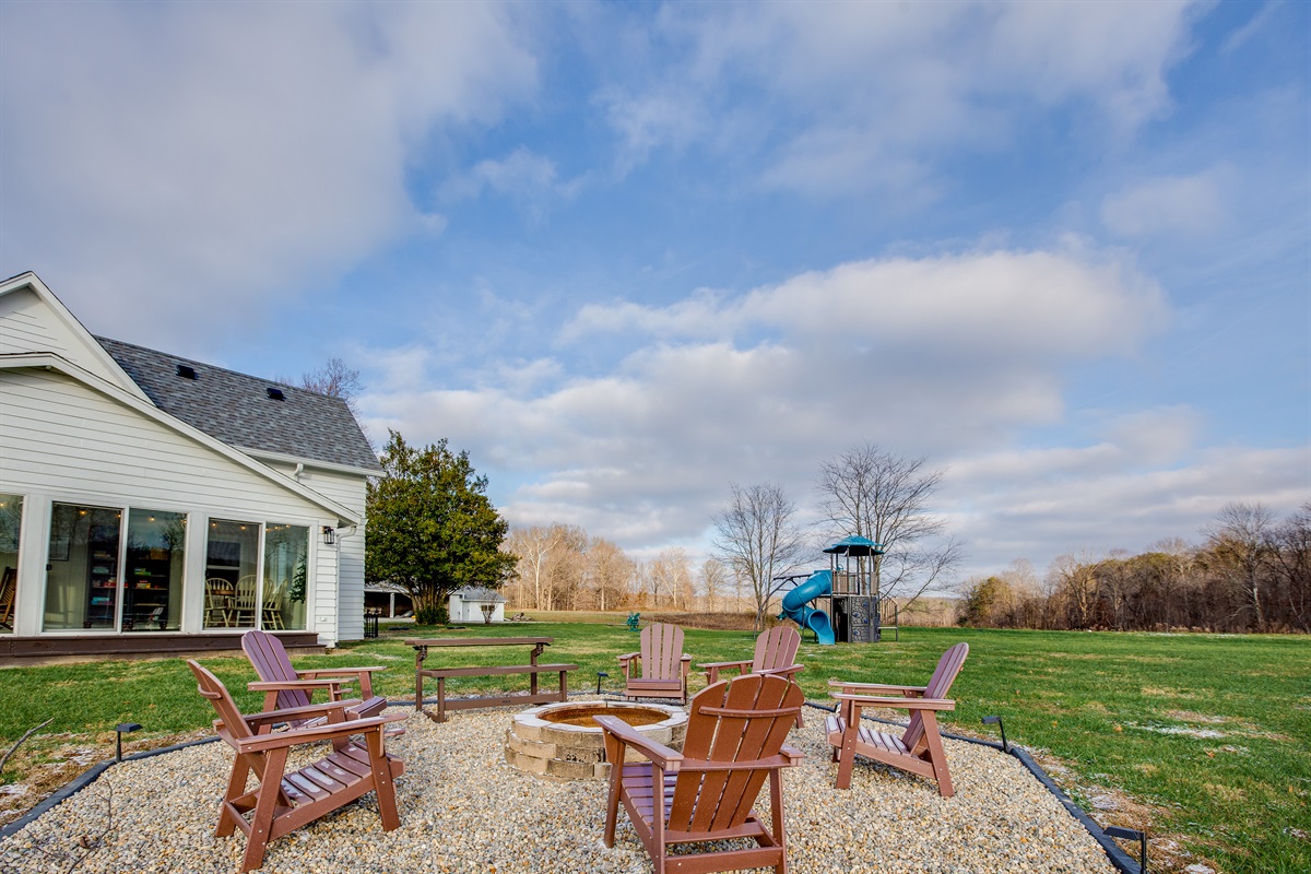 The backyard of the house (outside the sunroom) is home to the firepit and playground.  Past the house to the left you can see the game barn.