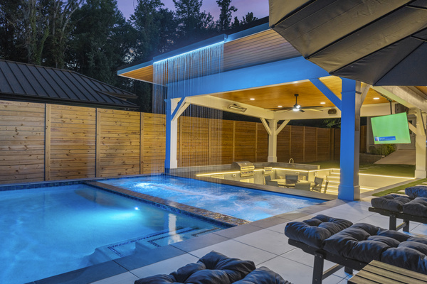 Hot tub spa with swim up bar and waterfall at night.