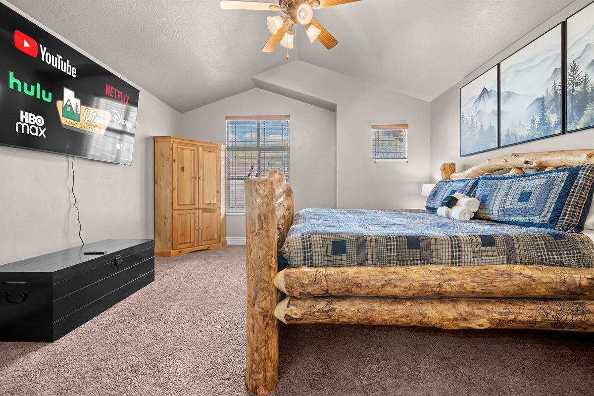 Spacious primary bedroom with a large smart TV and plenty of natural light.