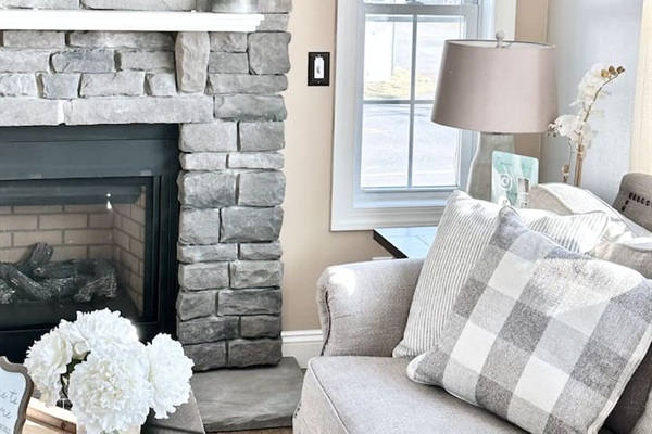Cozy up in this inviting armchair right next to the beautiful stone fireplace. With soft pillows and plenty of natural light, it’s a perfect little corner for guests to settle in with a good book or enjoy the warmth of the fire.