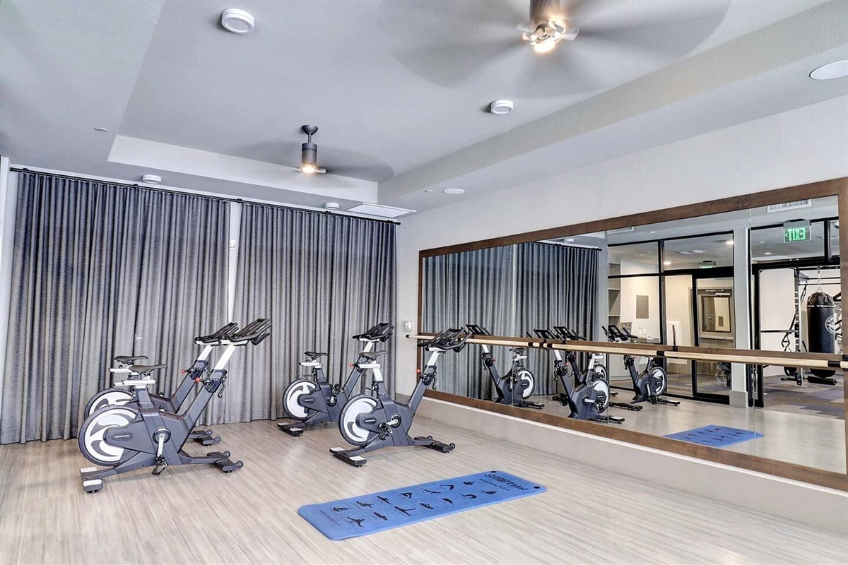 - Stay active in the bright fitness studio equipped with spin bikes and mirrors   - Ideal for yoga, stretching, or cardio sessions with natural light flowing in   - Modern design and spacious layout create a motivating workout environment