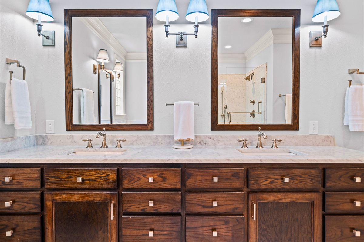 Double vanity and rich wood tones add warmth and space to this elegant bathroom.