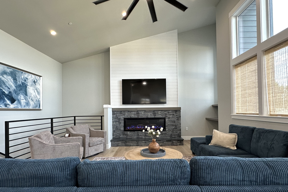 The great room anchors the main level: vaulted ceilings, a linear fireplace, a 75" smart TV, and a sectional deep enough for the whole crew.
