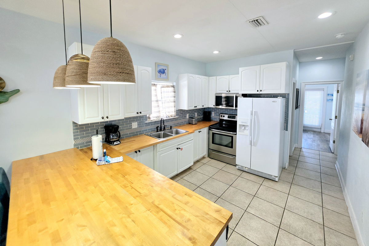 Kitchen with butcher-block counters, stainless range and microwave